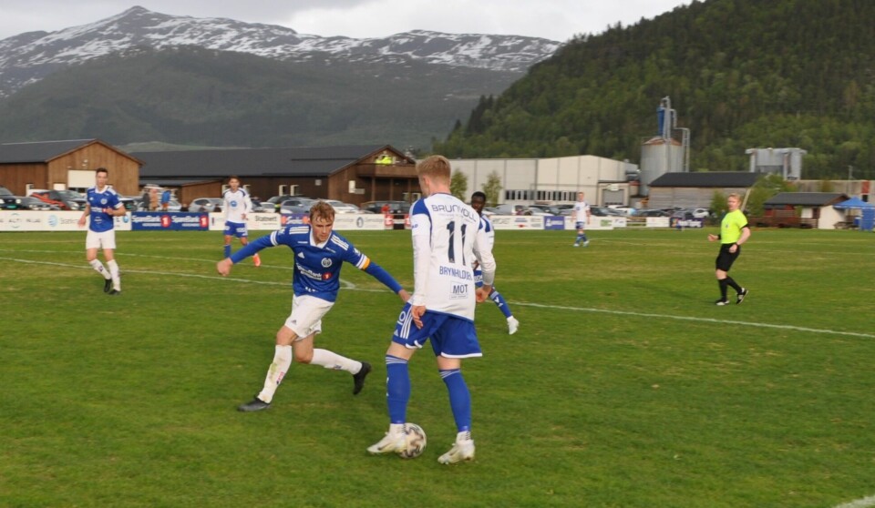 Fra en fotballkamp på Syltøran stadion. Surnadal  - Molde FK. To spillere kjemper om ballen.