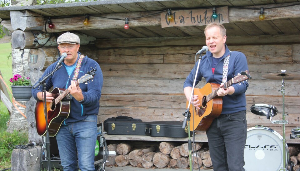 2 menn spiller gitar og synger i mikrofonene sine