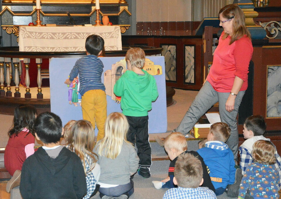 Barn holder på med diverse aktiviteter i kirka ved alteret