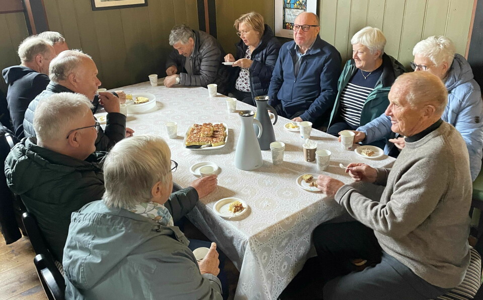 Eldre mennesker sitter rundt et bord og drikker kaffe og spiser vafler