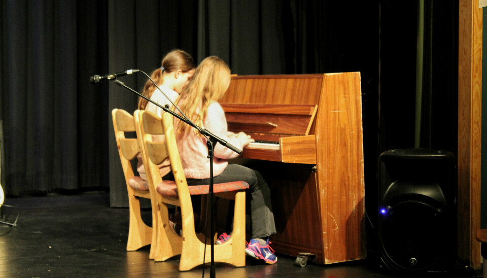 To jenter spiller på piano.
