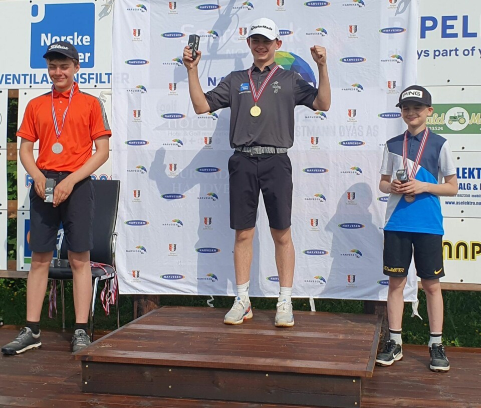 3 unge gutter står på en pall med første, andre og tredje plass