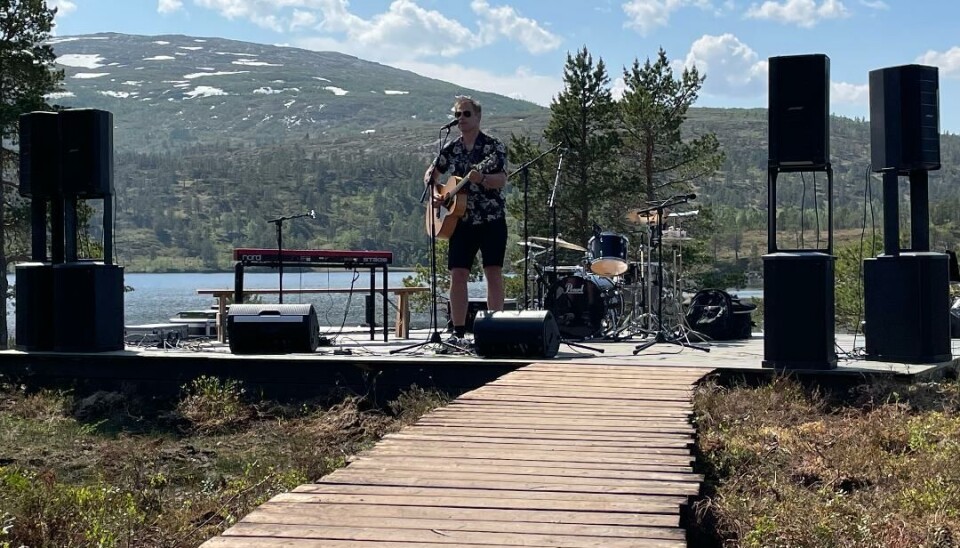 Mann med gitar spiller og synger i mikrofon