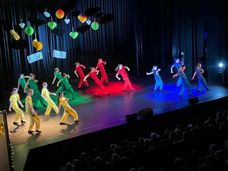 Fire gange fire barn kledd i gult, og like mange av hver i grønt, rødt og blått. De danser i hver sine grupper.