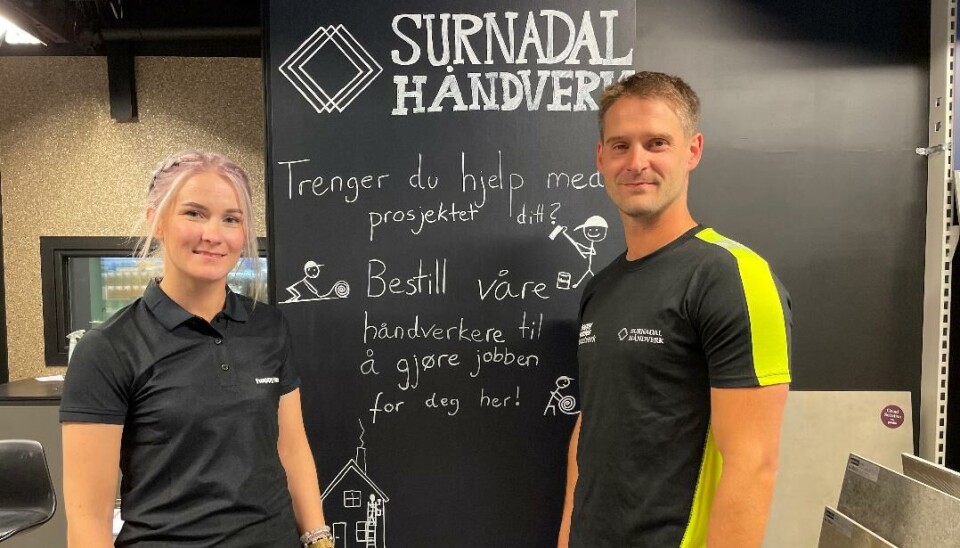 Mari Ranes Eidsli nominerte Tony Sæterbø i Surnadal Håndverk til konkurransen En dame og en mann står foran en tavle hvor det står 'SURNADAL HÅNDVERK' med mer tekst og tegninger.