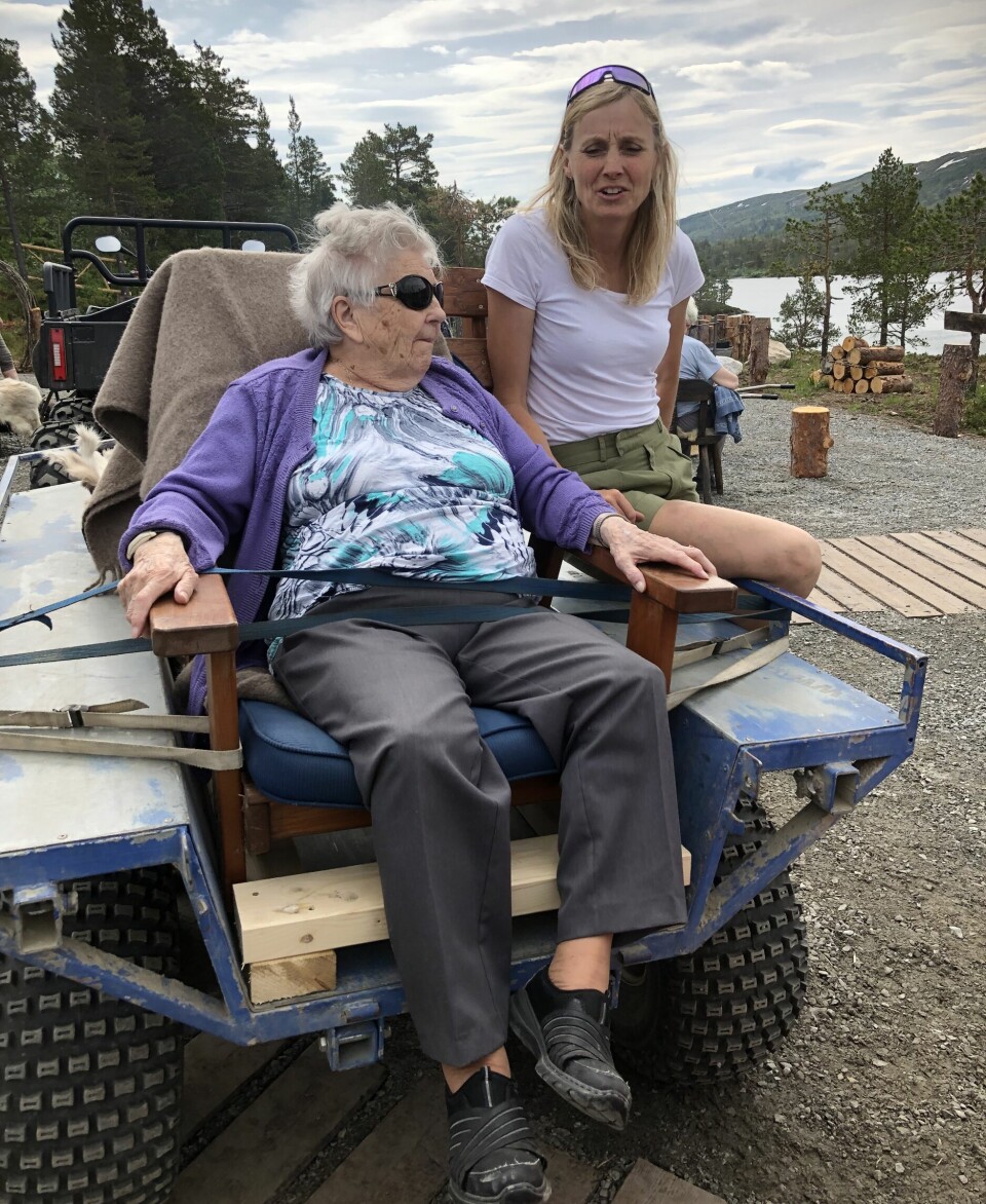 En eldre dame sitter bak et kjøretøy og snakker med en annen kvinne