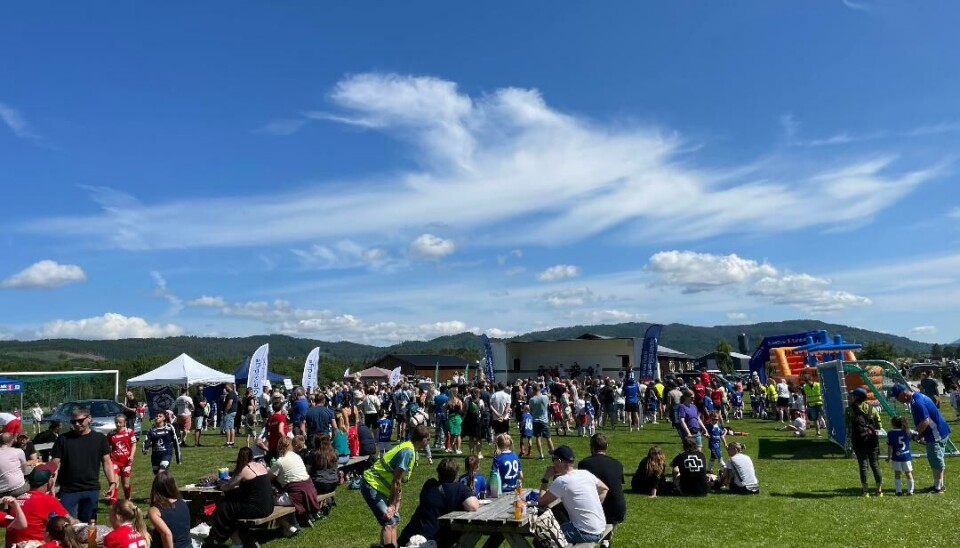 Masse mennesker sitter på benker og står på minifestivalområdet.