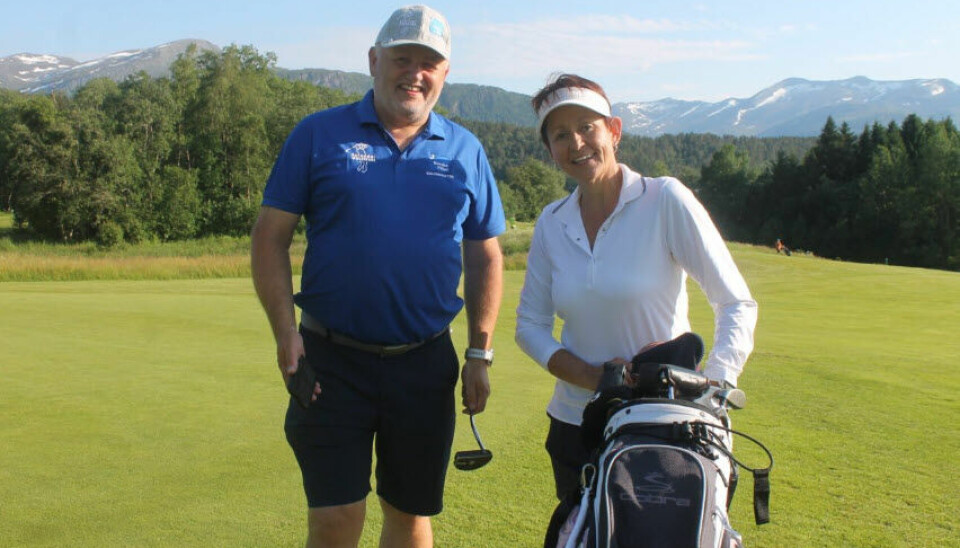 En mann og en damme står på en golfbane med golfutstyr
