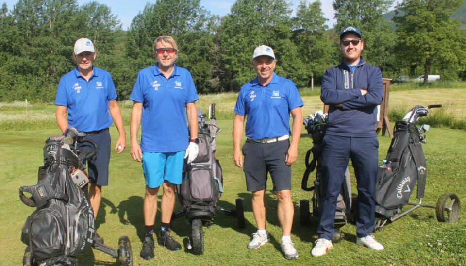 4 menn smiler mot kameraet med golfutstyret sitt