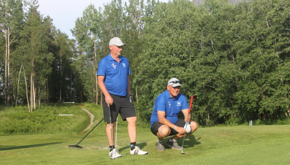 To menn står på en golfbane med golfutstyr