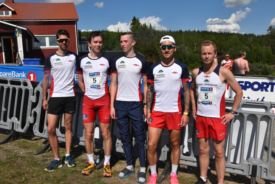 Fem menn kledd i Rindal IL løperklær, oppstilt ved siden av hverandre på et sportsstadion.