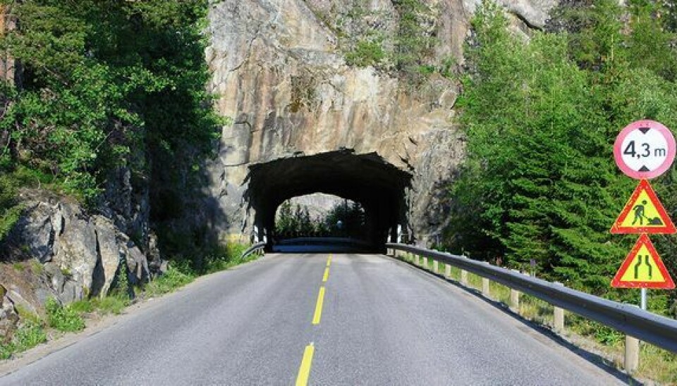 En tunnel gjennom en fjellvegg, før tunnelen er det skilt om veiarbeid
