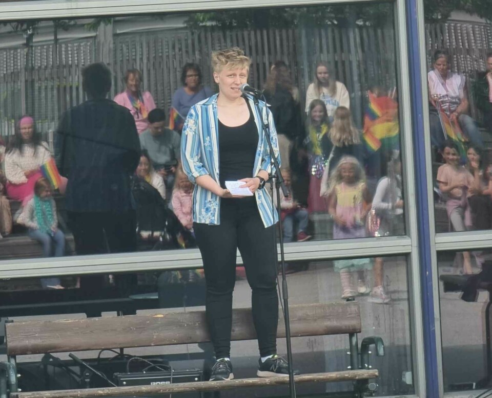 En kvinne står på en benk og prater i en mikrofon