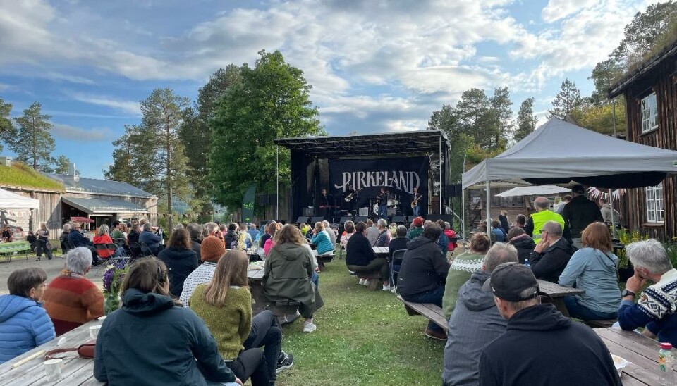 Fullt av folk sittende foran scenen på benker med bord