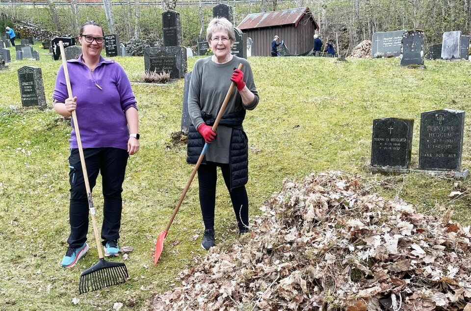 To kvinner står på en kirkegård og raker opp løv