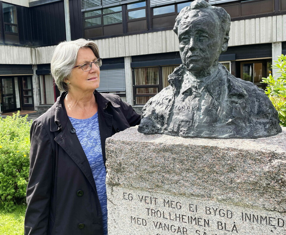 En kvinne står ved siden av en statue av hodet til Hans Hyldbakk