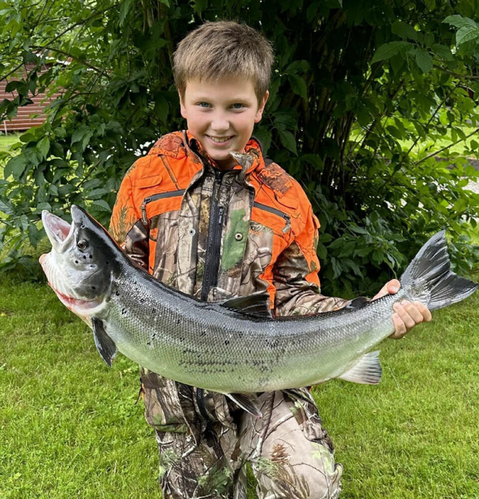 En smilende ung gutt som holder en stor fisk.