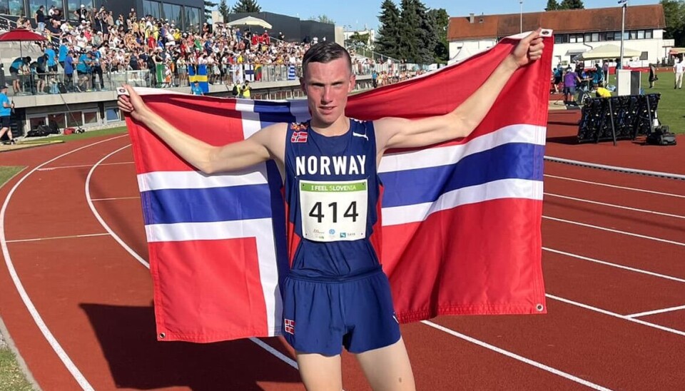 Magnus Øyen skal løpe 1500 m under European Athletics U18 Championships. Her fra i fjor sommer da han tok sølv på 3000m i EYOF. En ung mann i løperdrakt på en friidrettsstadion, med et norsk flagg bak ryggen.