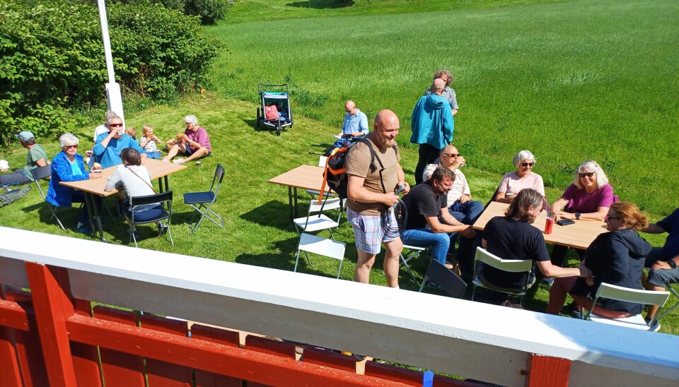 Mennesker sitter ved bord på stoler og spiser mat utendørs
