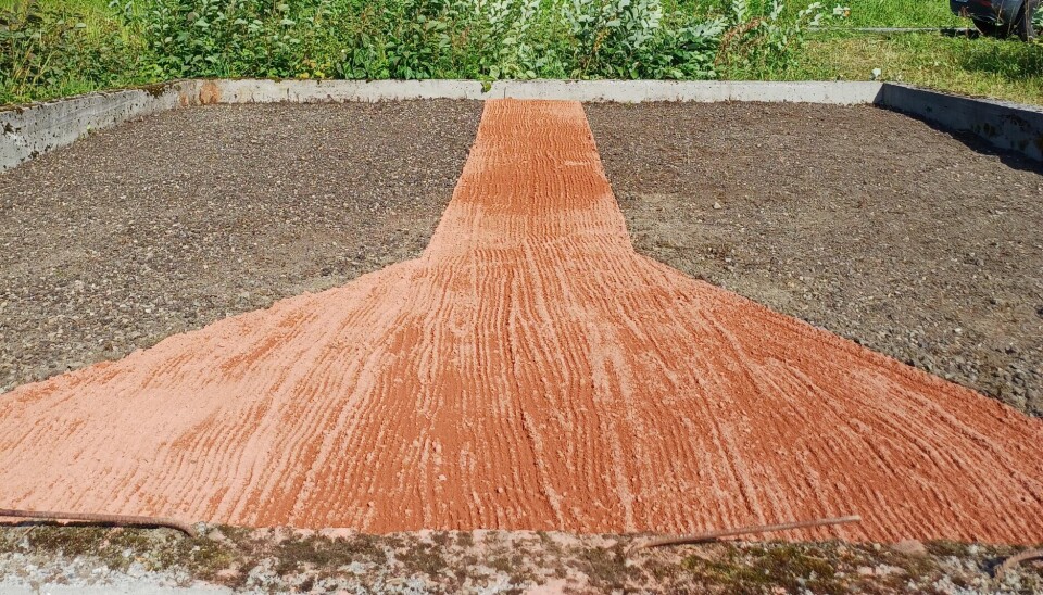 En kasse med sand og oransje sand som lager et mønster