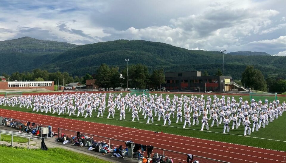 Fullt av folk på rekke og rad står i samme posisjon og alle har Taekwon-Do-klær