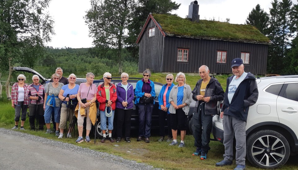 En rekke med eldre mennesker står klare til tur foran biler ved en hytte