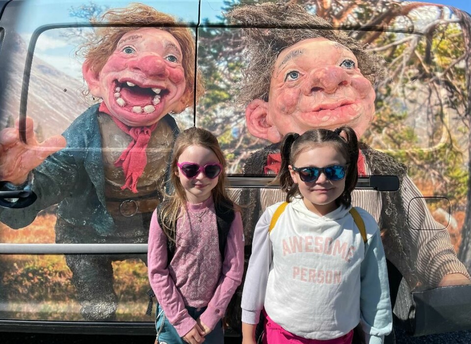 To jenter foran bilde av to troll.