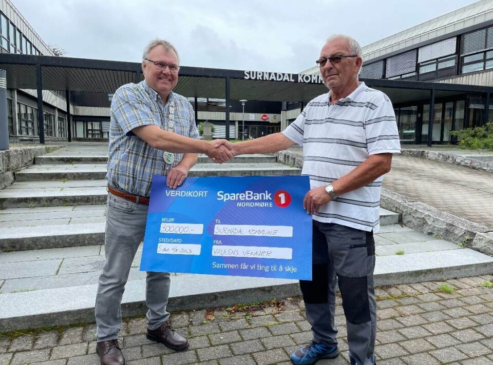 Varaordfører Hugo Pedersen takker Per Heggset og Vaulens venner for den store pengegaven, og lover å ta godt vare på Vaulen. To menn tar hverandre i hånden mens de holder en gavesjekk.