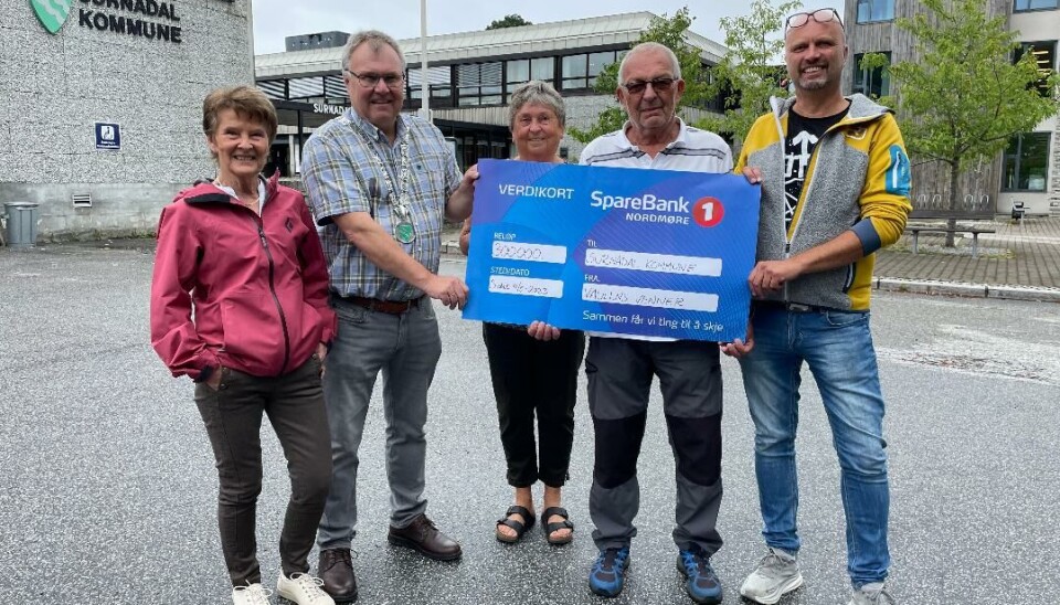 Surnadal kommune får en gavesjekk på 300.000 kroner av Vaulens venner. Fra venstre: Ann Grete Gravvold, Hugo Pedersen, Mary Moen, Per Heggset og Olav Arne Settemsdal. Fem voksne står foran kommunehuset. Gavesjekk.