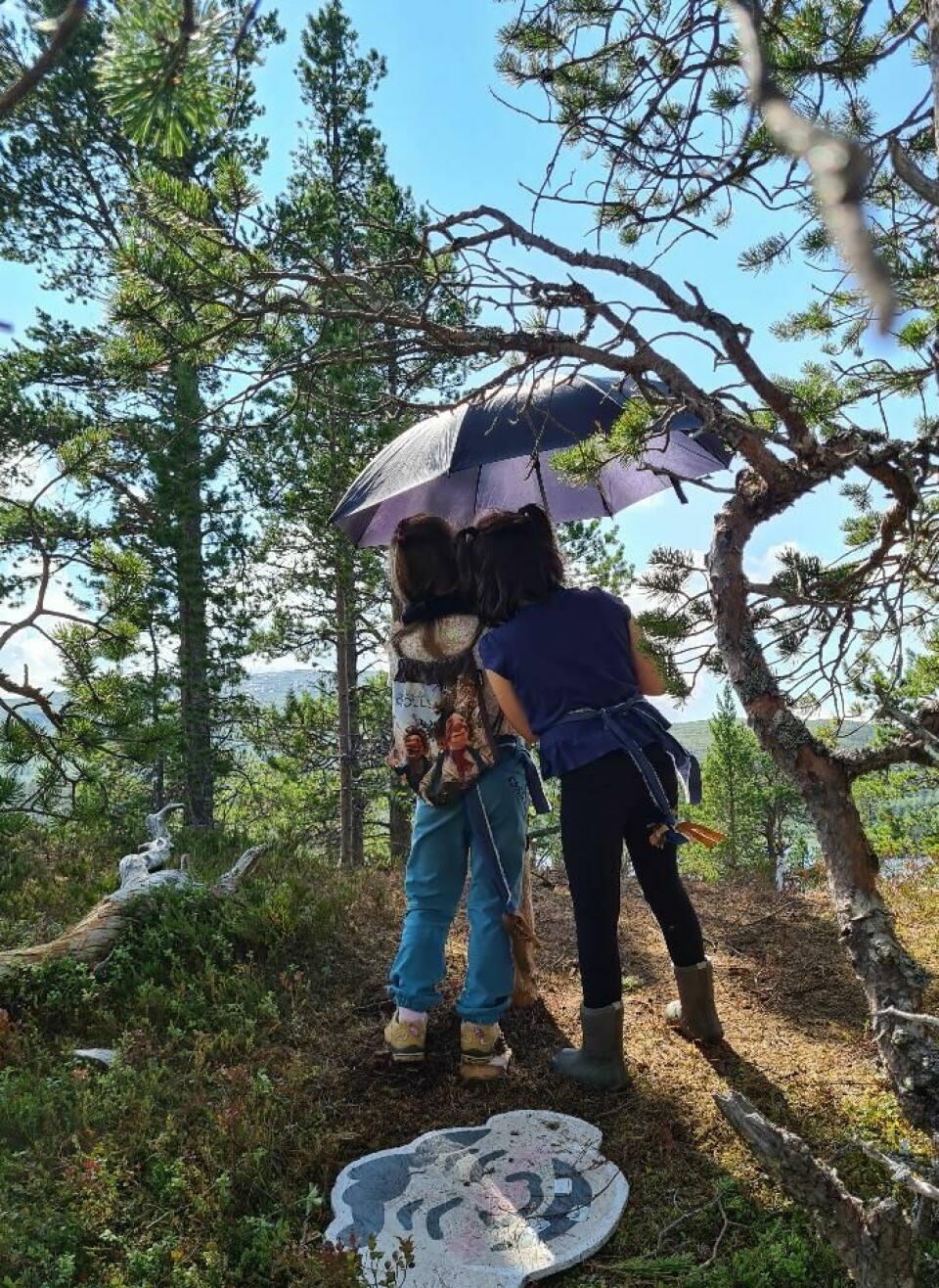 To jenter med sekk og paraply.