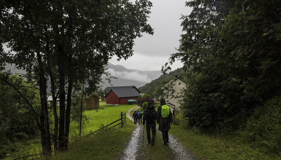 Mennesker går nedover en slak bakke mens det regner kraftig