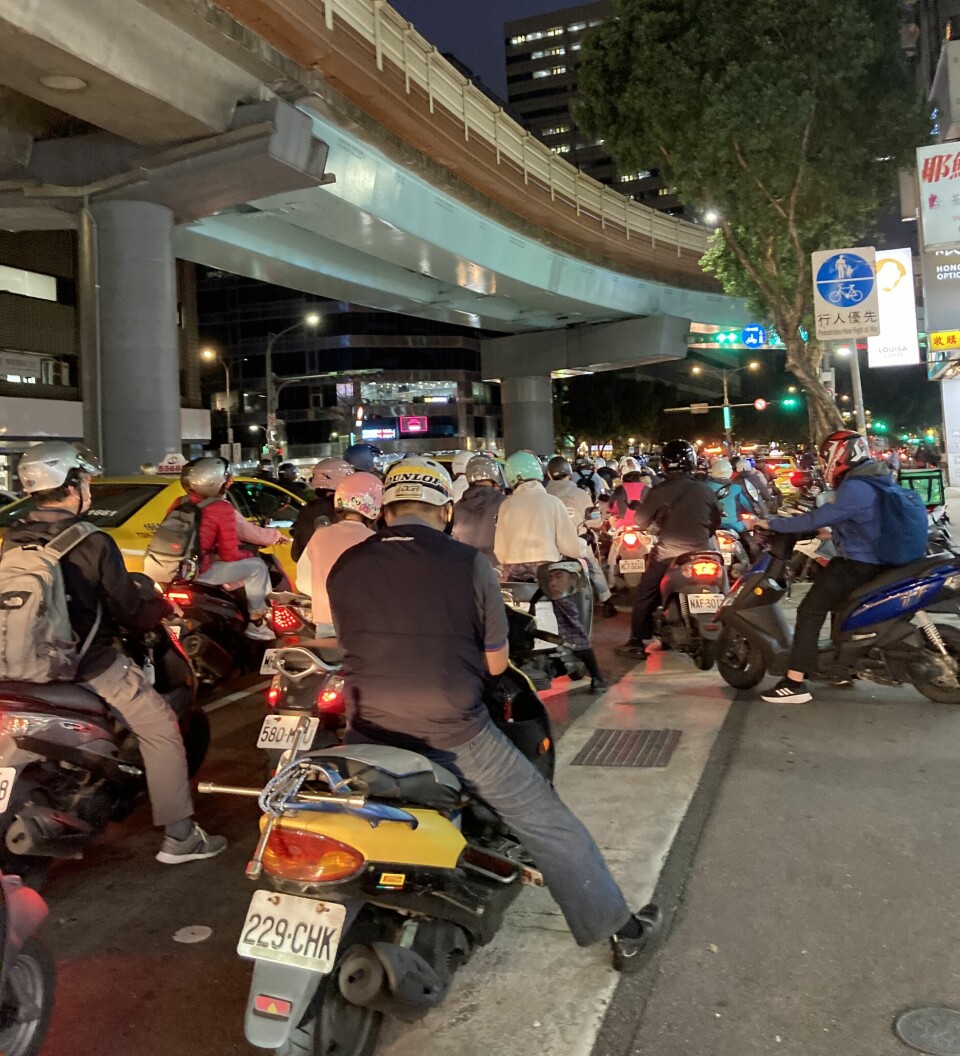 Fra ei gate i et asiatisk land, full av folk og motorsykler.
