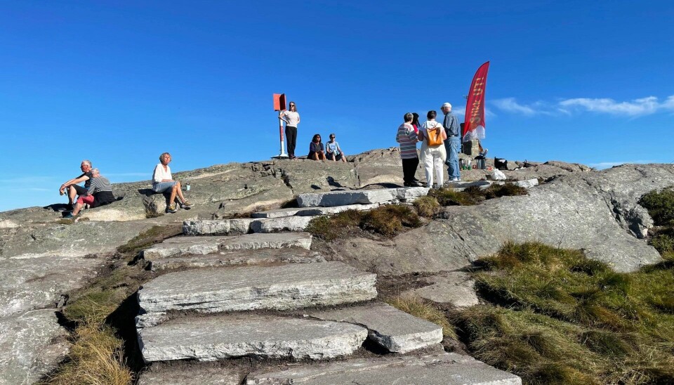 Omkring ti mennesker sitter og står på et fjell