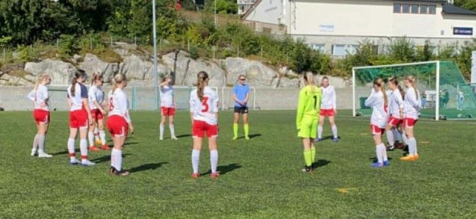 Et fotballag med unge jenter på en fotballbane.