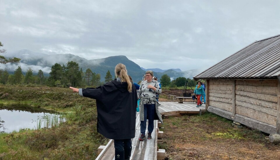 Tjønn, sti av treplanker, mennesker og gapahuk.