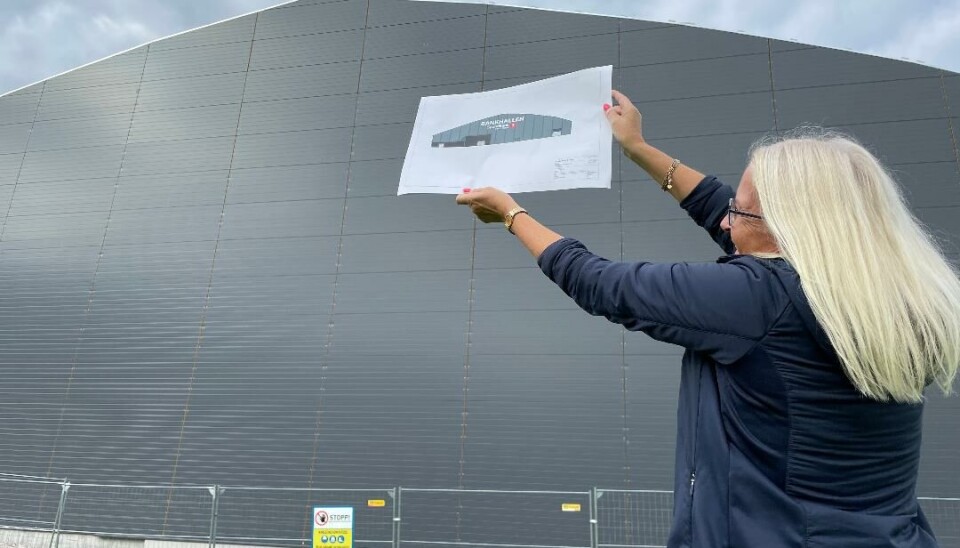 Dame holder oppe et ark foran veggen til hallen som holder på å komme opp.