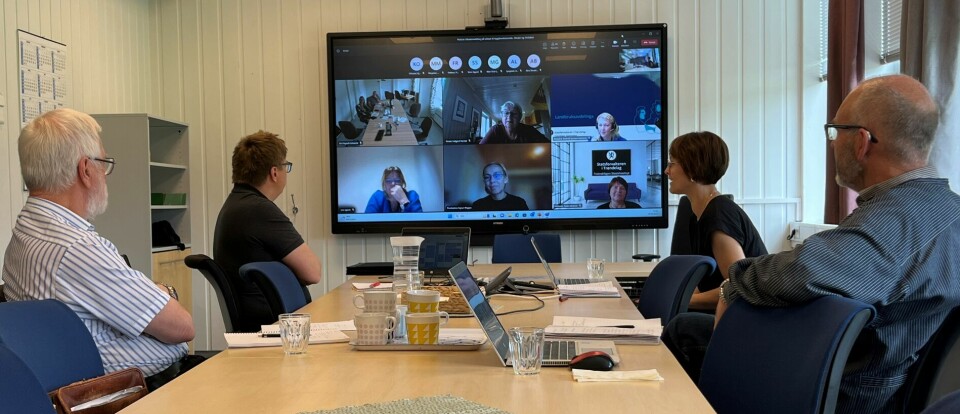 Fire møtedeltakere i et mlterom kommunsierer med andre møtedeltakere på storskjerm.