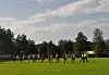 Dommere og mange fotballspillere på gressbane.