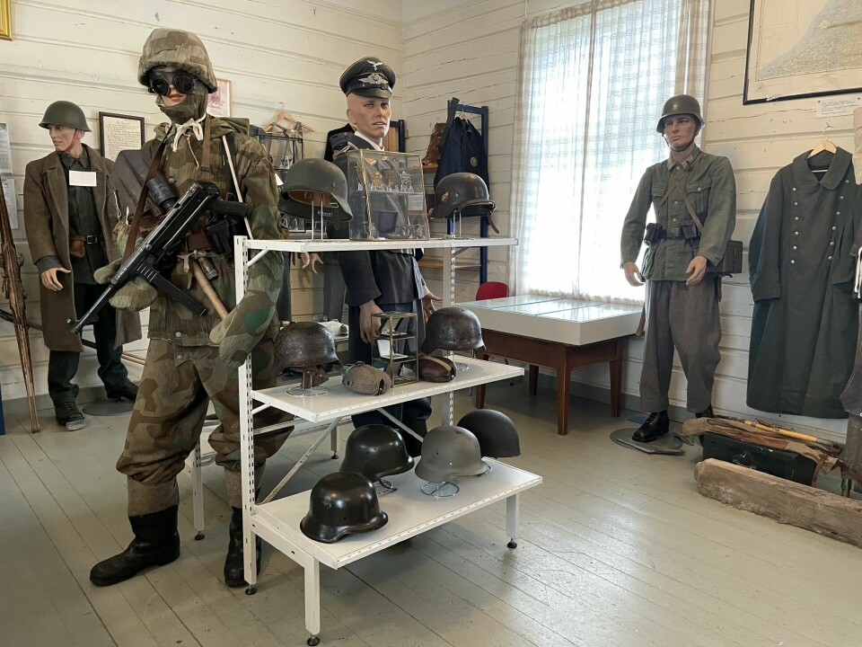 Dukker med krigsklær og -utstyr, stativ med hjelmer