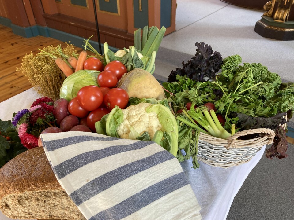 Rt bord med brød og grønnsaker inne i ei kirke.