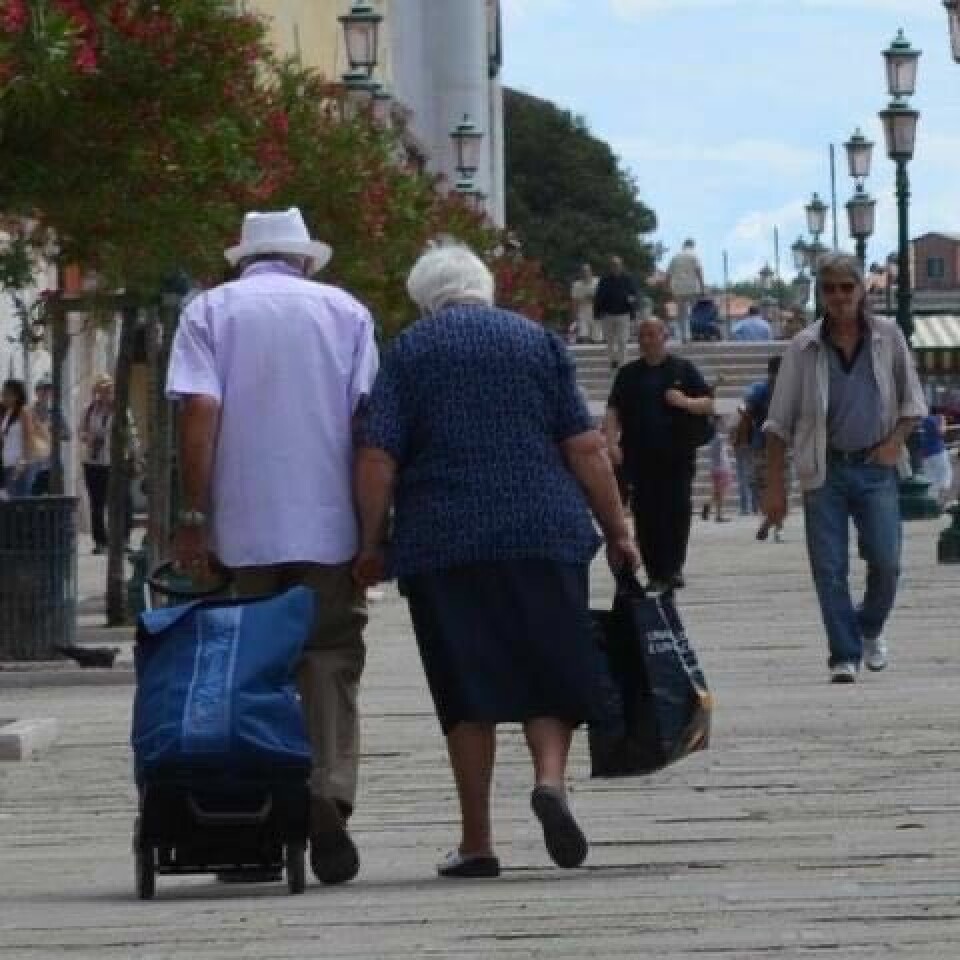 Eldre mann og eldre dame går hånd i hånd