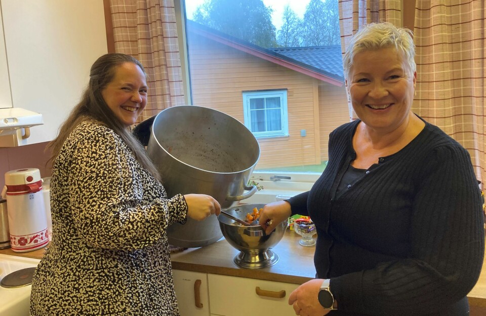 To blide damer som øser opp suppe på et kjøkken.