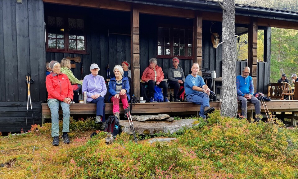 Ei gruppe turkledde pensjonister som tar en rast ved ei hytte.