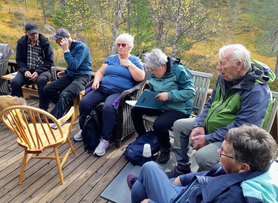 Ei gruppe turkledde pensjonister som tar en rast ved ei hytte.