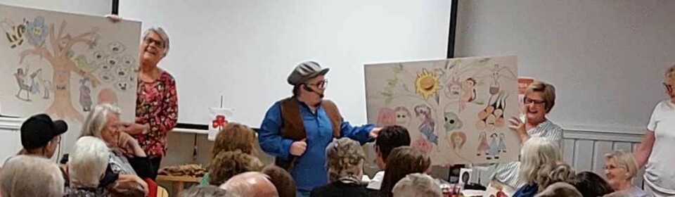 To kvinner viser fram tegninger for en forsamling