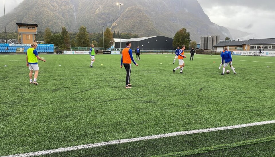 Et fotballag med blå drakter står på en fotballbane.