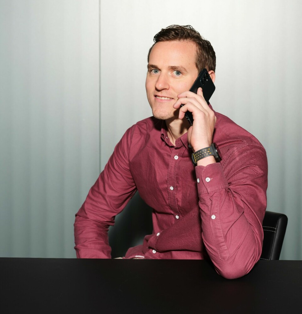 En mann med røs skjorte snakker i telefonen