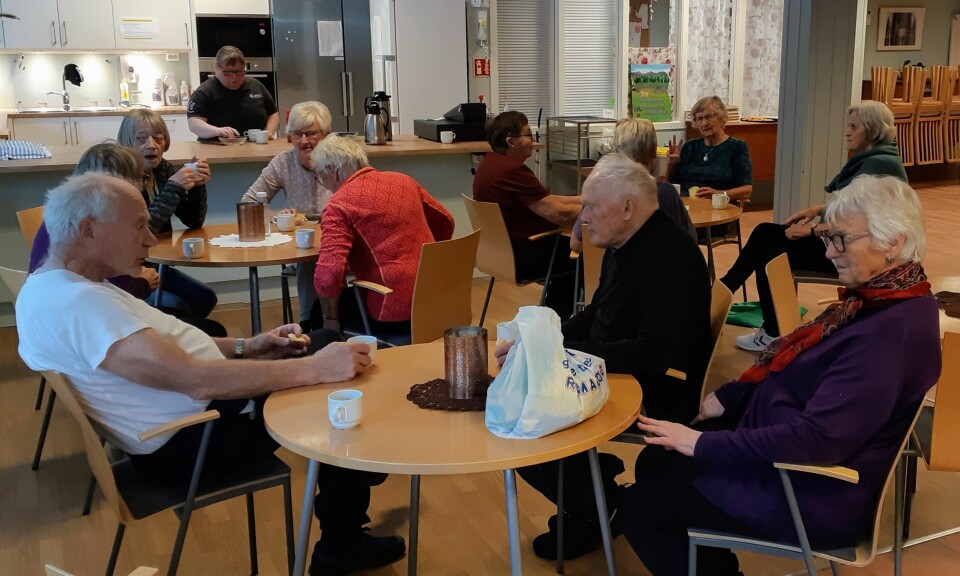 Ei gruppe pensjonister som sitter fordelt rundt tre kafebord.