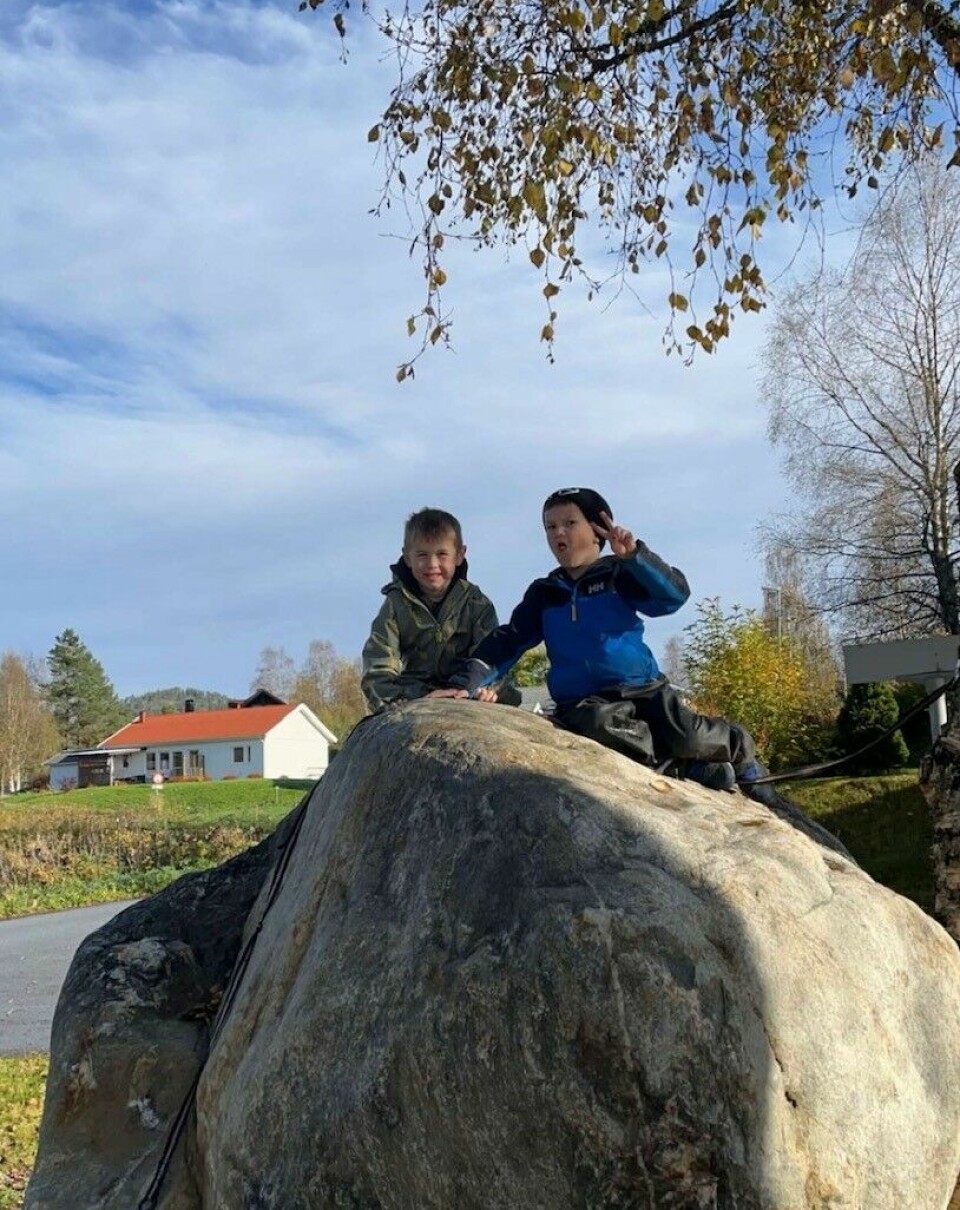 To barn som sitter oppå en stor stein.