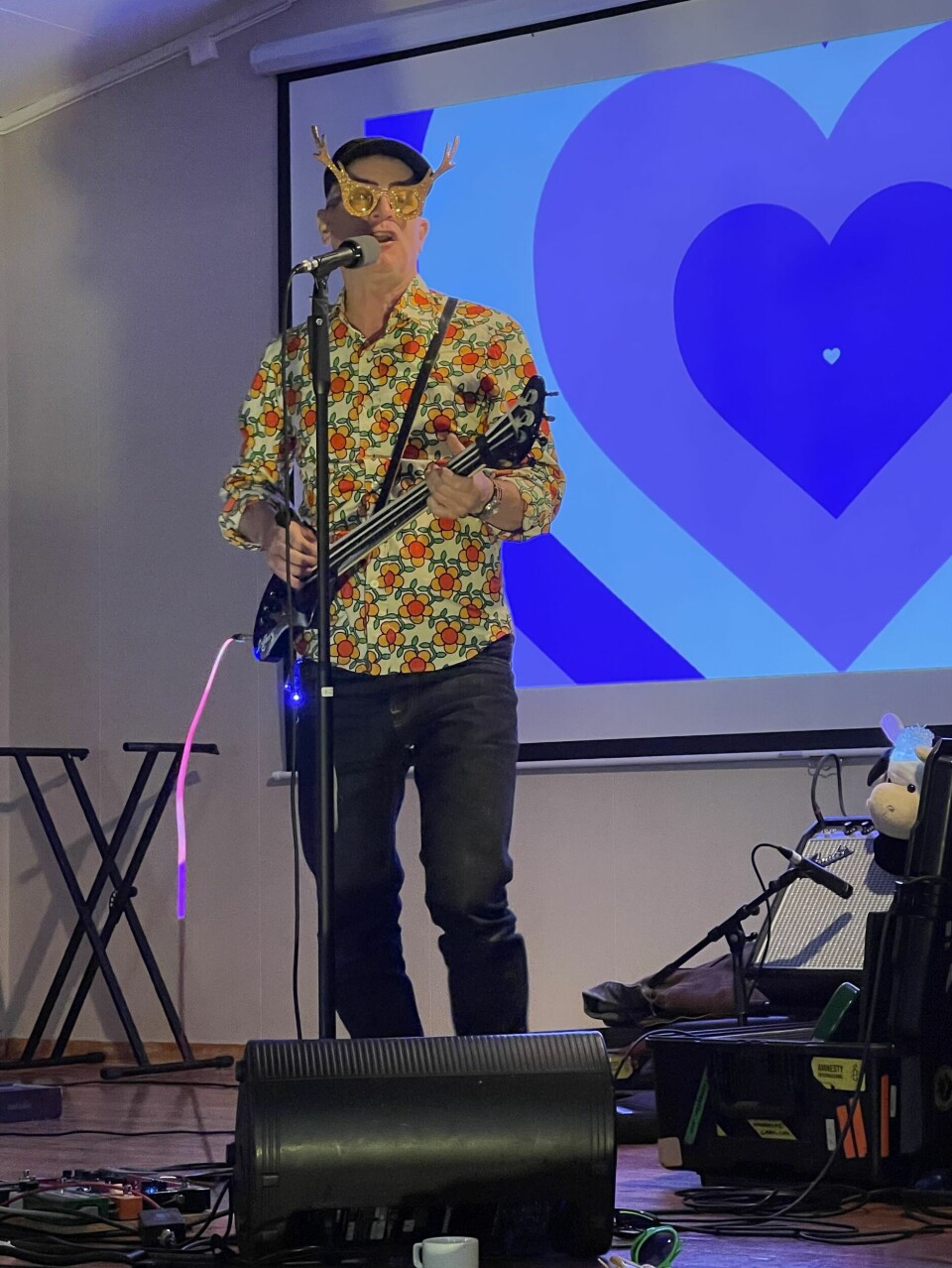 En mann med hatt og rare briller spiller el-gitar på en scene